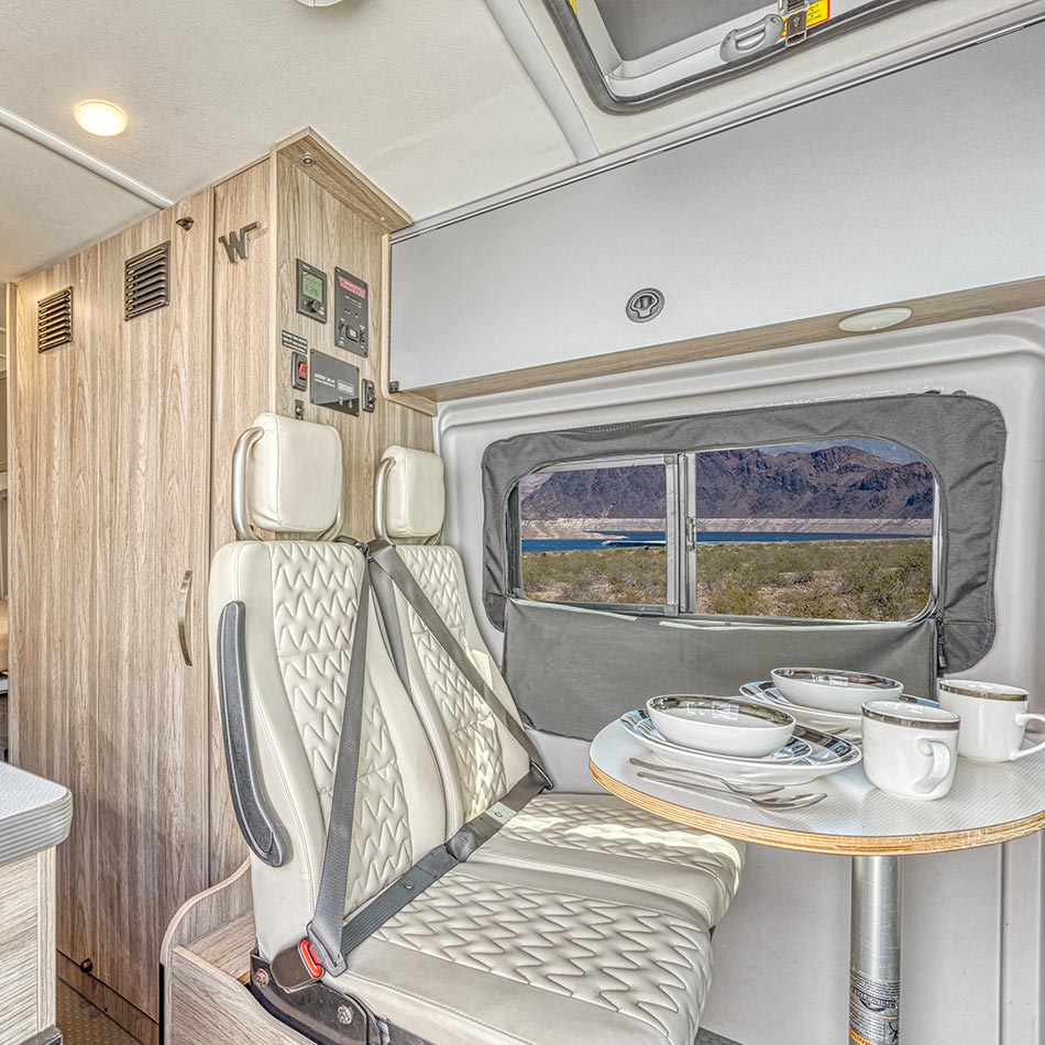 The dining area with a compact table, two seats and a window onto a desert lake view