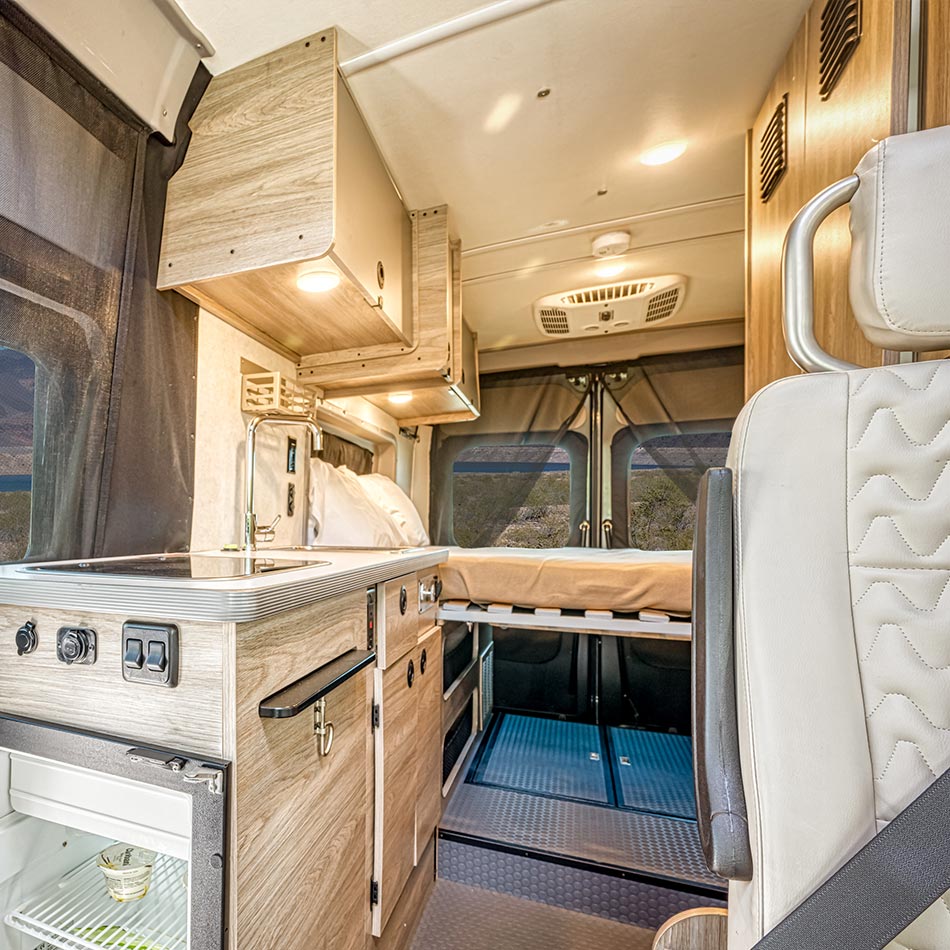 The kitchen with a two-ring hob, sink and fridge looking through to the rear bed