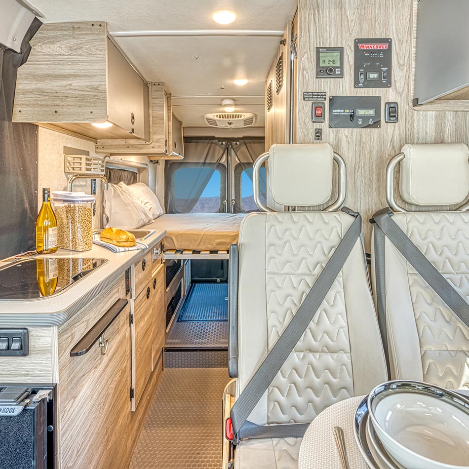 The lounge area with swivel cab seats facing the rear bed, kitchen along the side